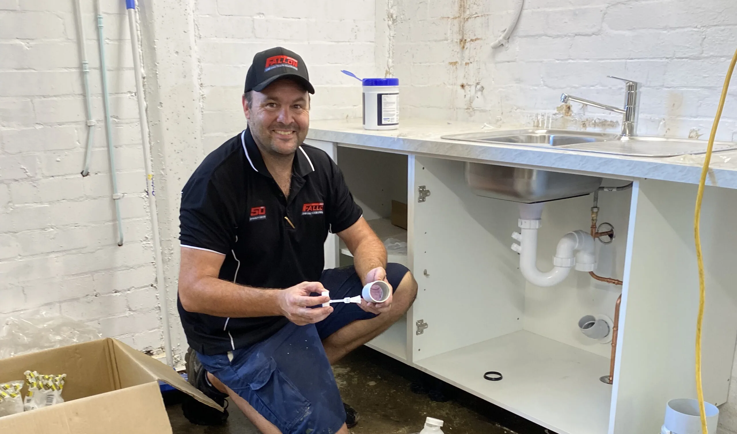 Fallon Solutions master plumber installing new under sink piping in a kitchen rennovation.