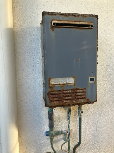 old rusted everhot gas hot water unit to be replaced at a property in Broadbeach